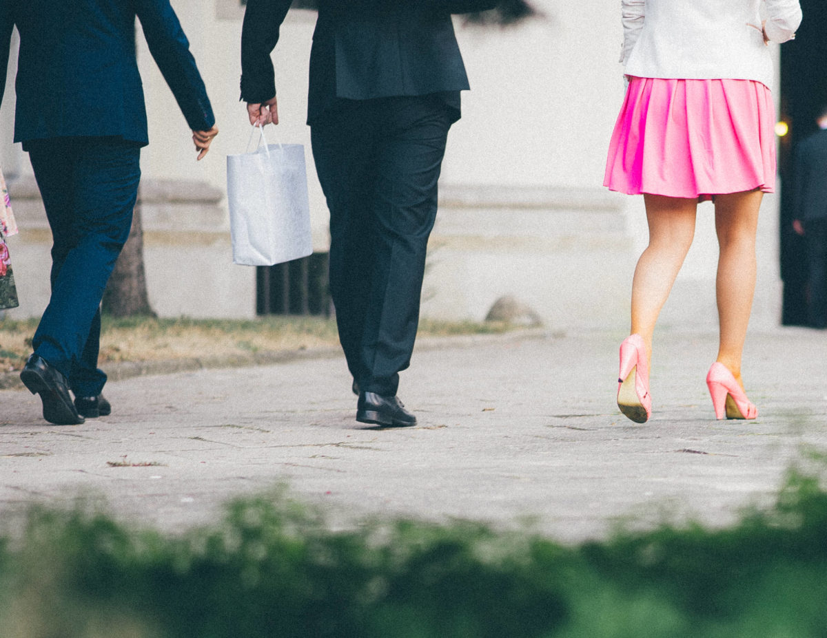Two business men and one business women walking away, one man holding a bag